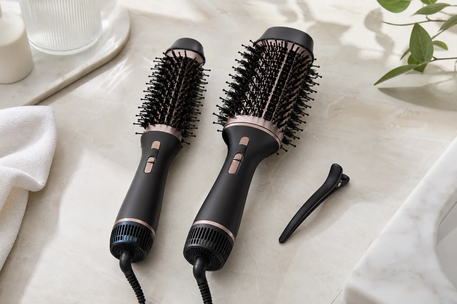 Two hot air brushes with different barrel widths lying beside a sectioning clip