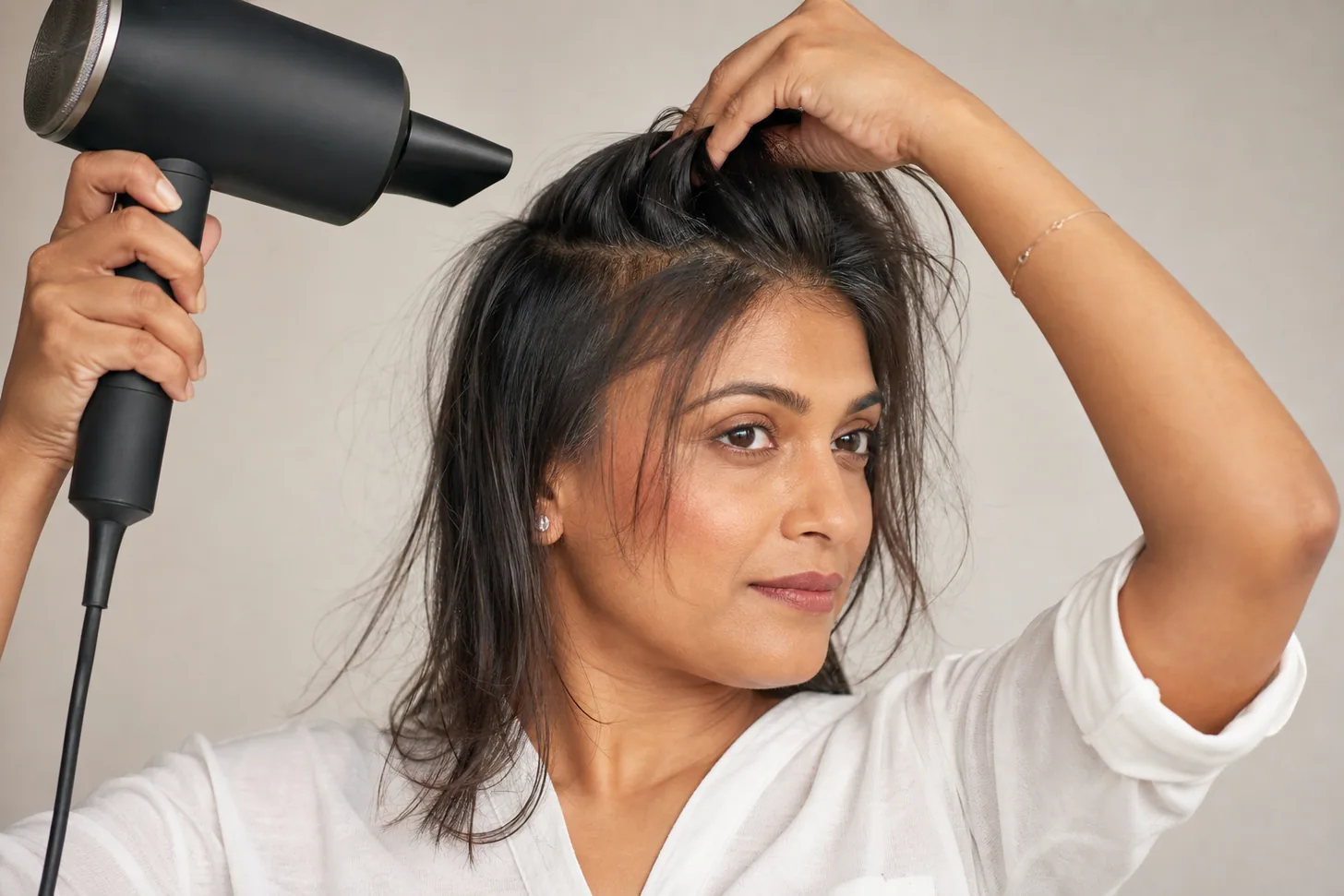 Rough-drying the roots of fine hair with fingers on medium heat to build lift before the round brush