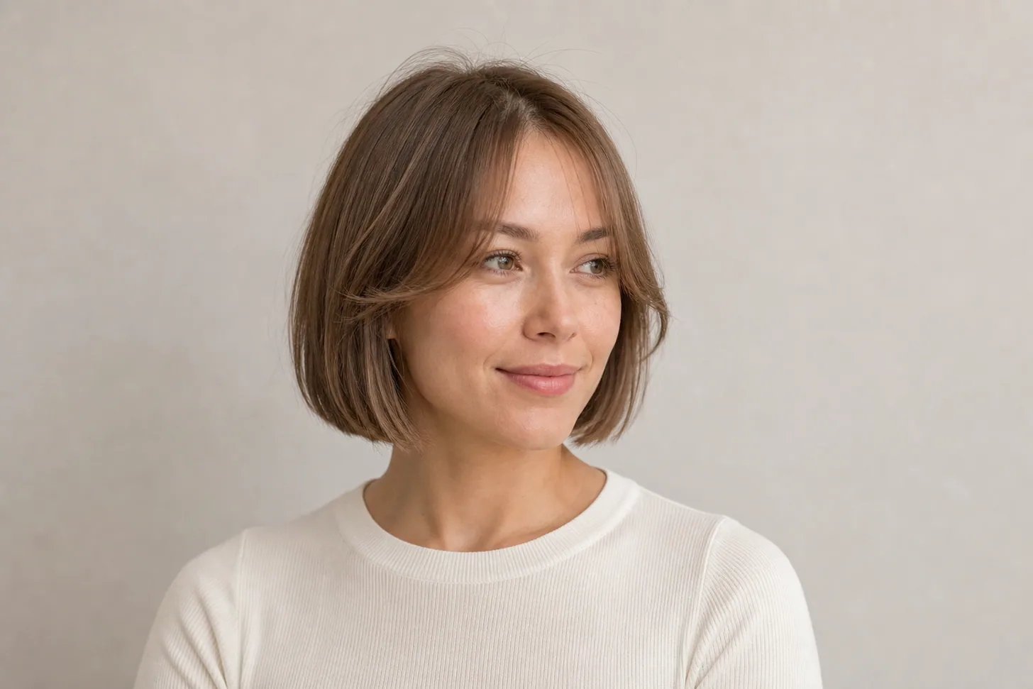 Chin-length bob with soft curtain bangs on fine light-brown hair