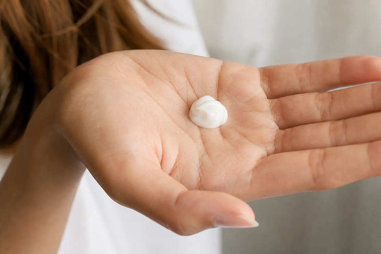 A small coin-sized amount of lightweight conditioner in an open palm for fine hair