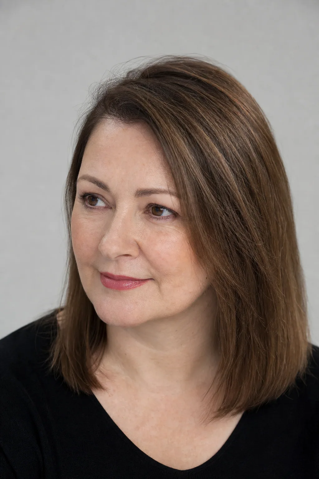 Mid-length cut worn with a deep side part lifting the crown and sweeping fuller hair to one side on fine straight hair, woman with a round face