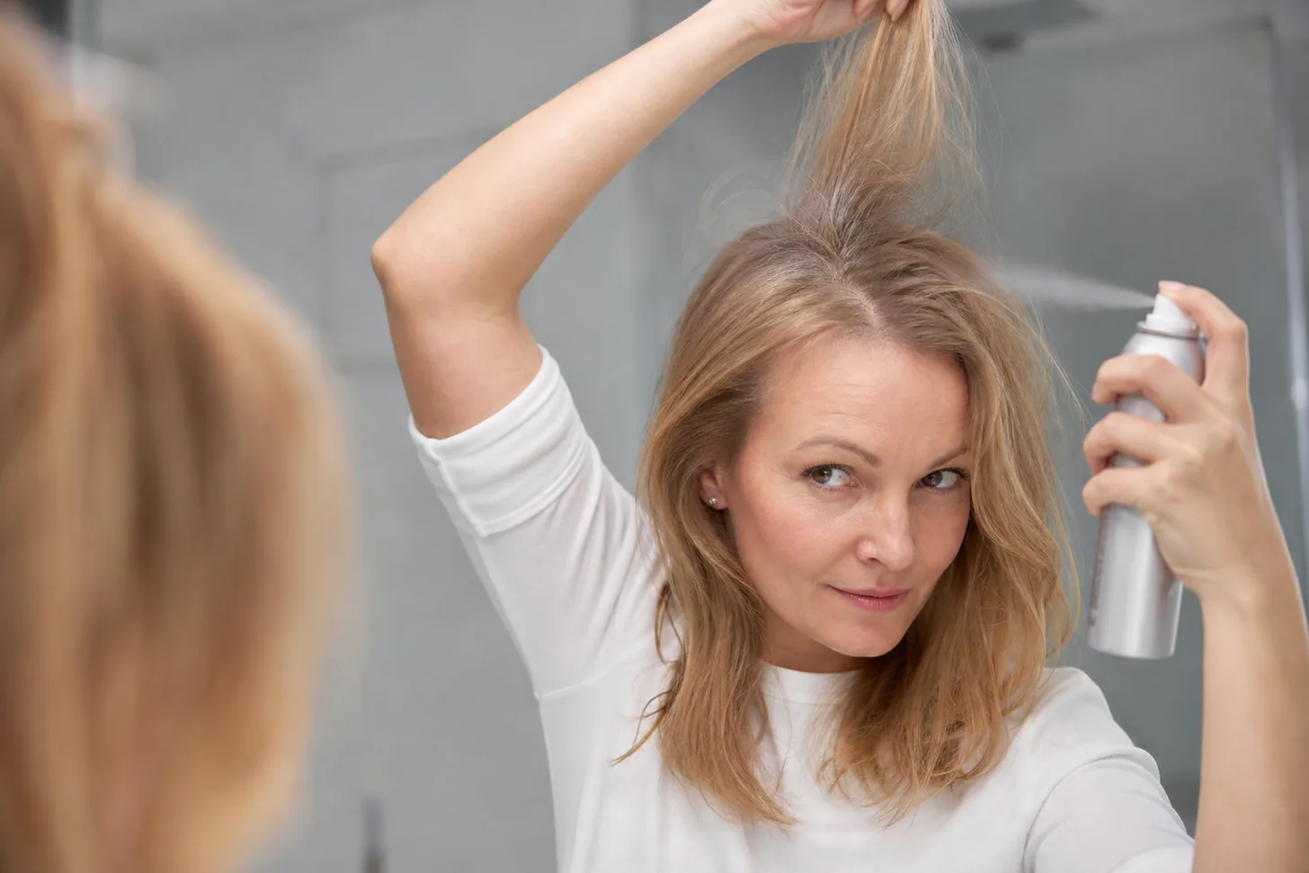 Dry shampoo sprayed at the roots of sectioned fine hair from a distance