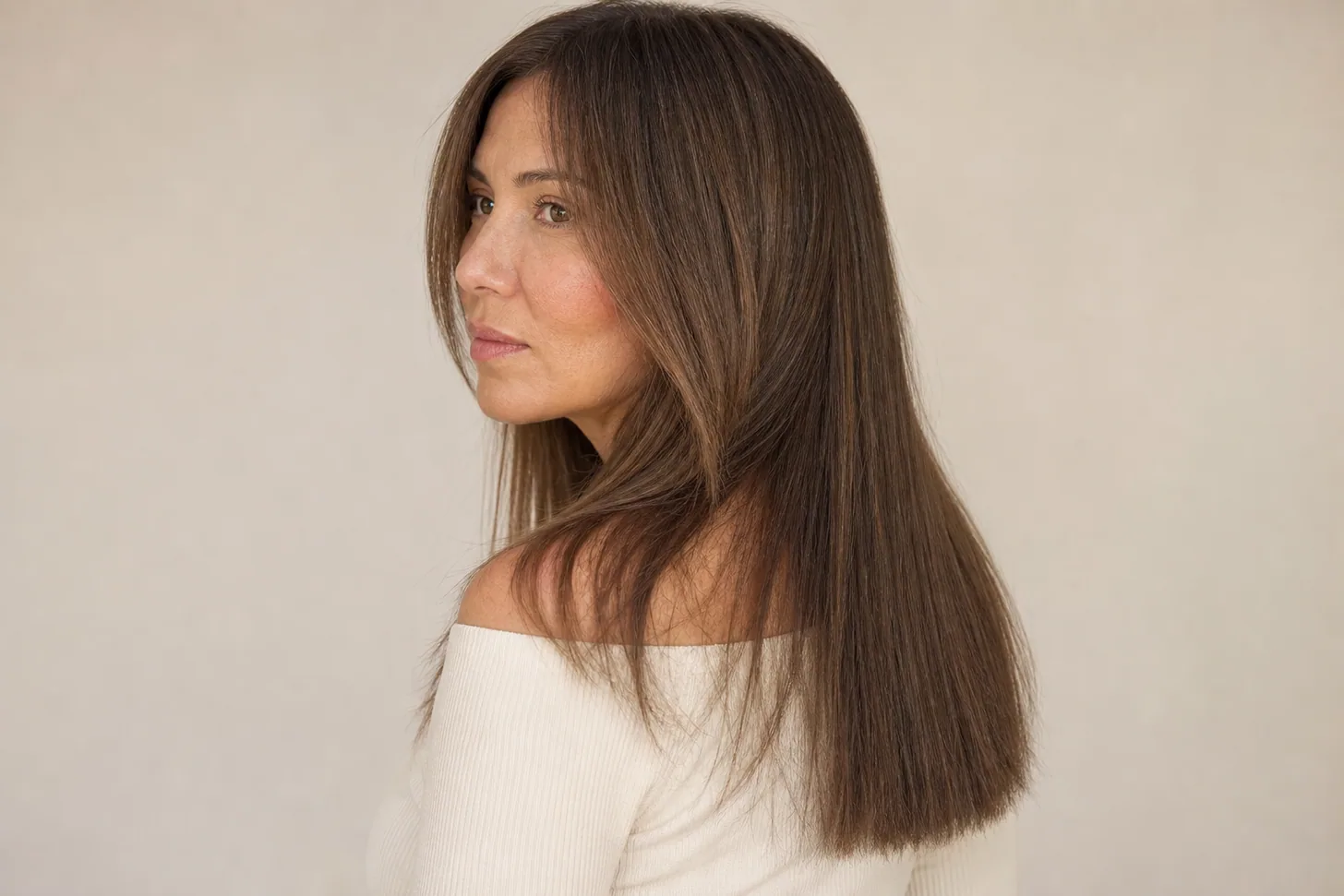 Three-quarter view of long fine mid-brown hair with ghost layers — one-length blunt perimeter, visible lift and depth through the mid-lengths