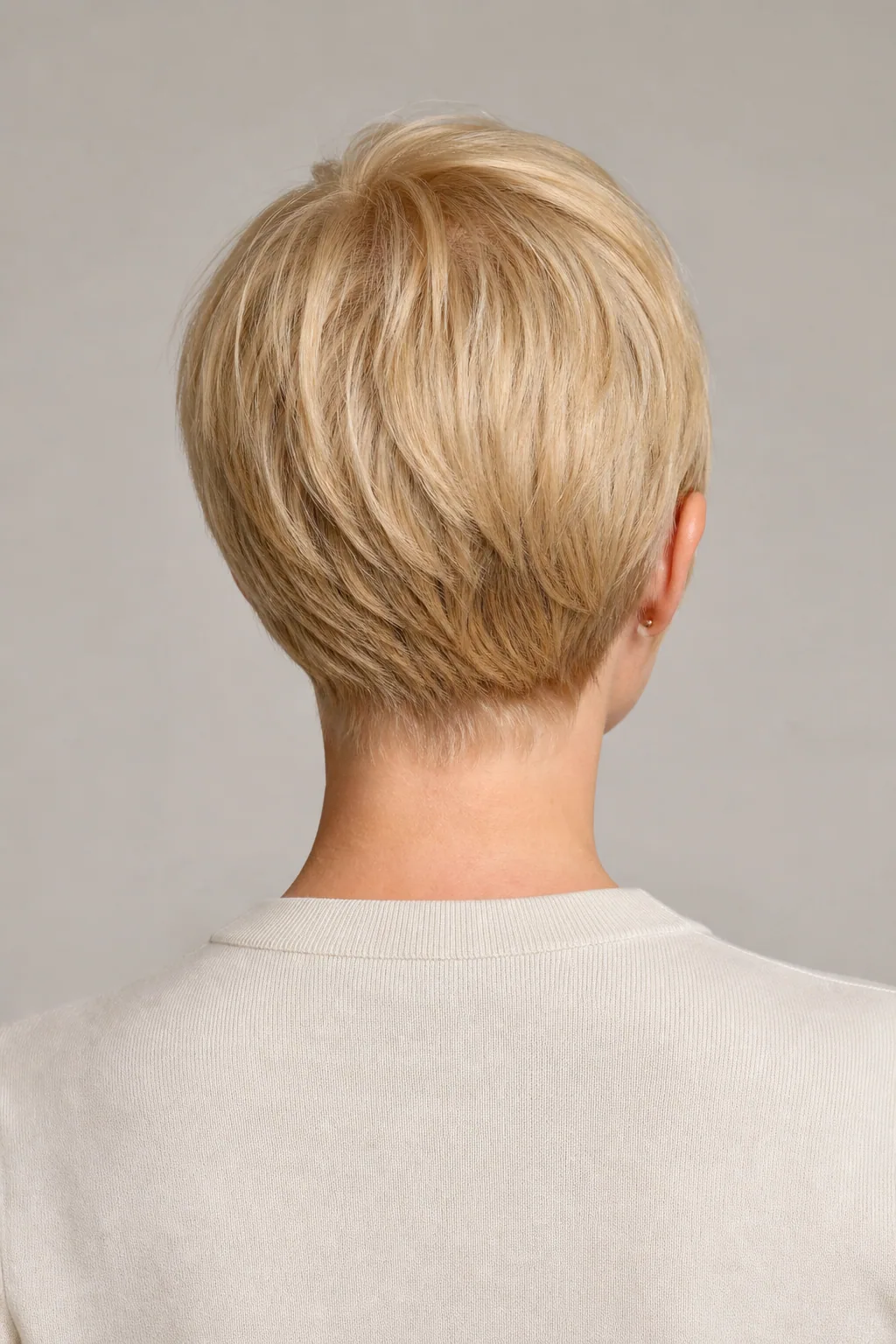 Back view of a soft pixie with a small hidden nape undercut on fine blond hair