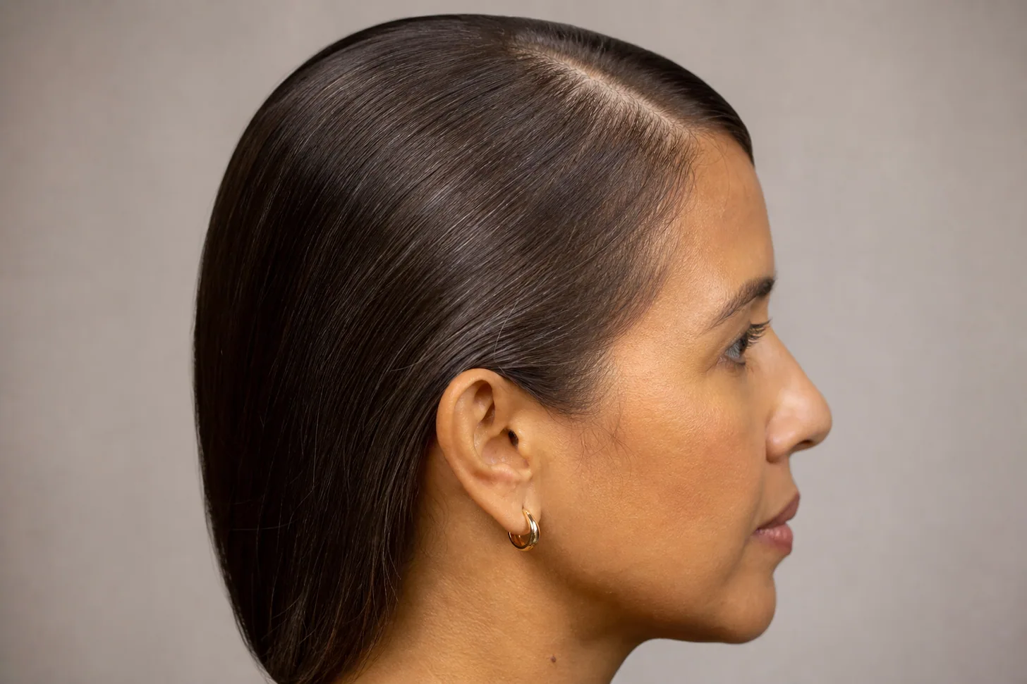 Side profile of fine hair after a smoothing treatment, lying flat against the head with no root lift and a clearly visible parting