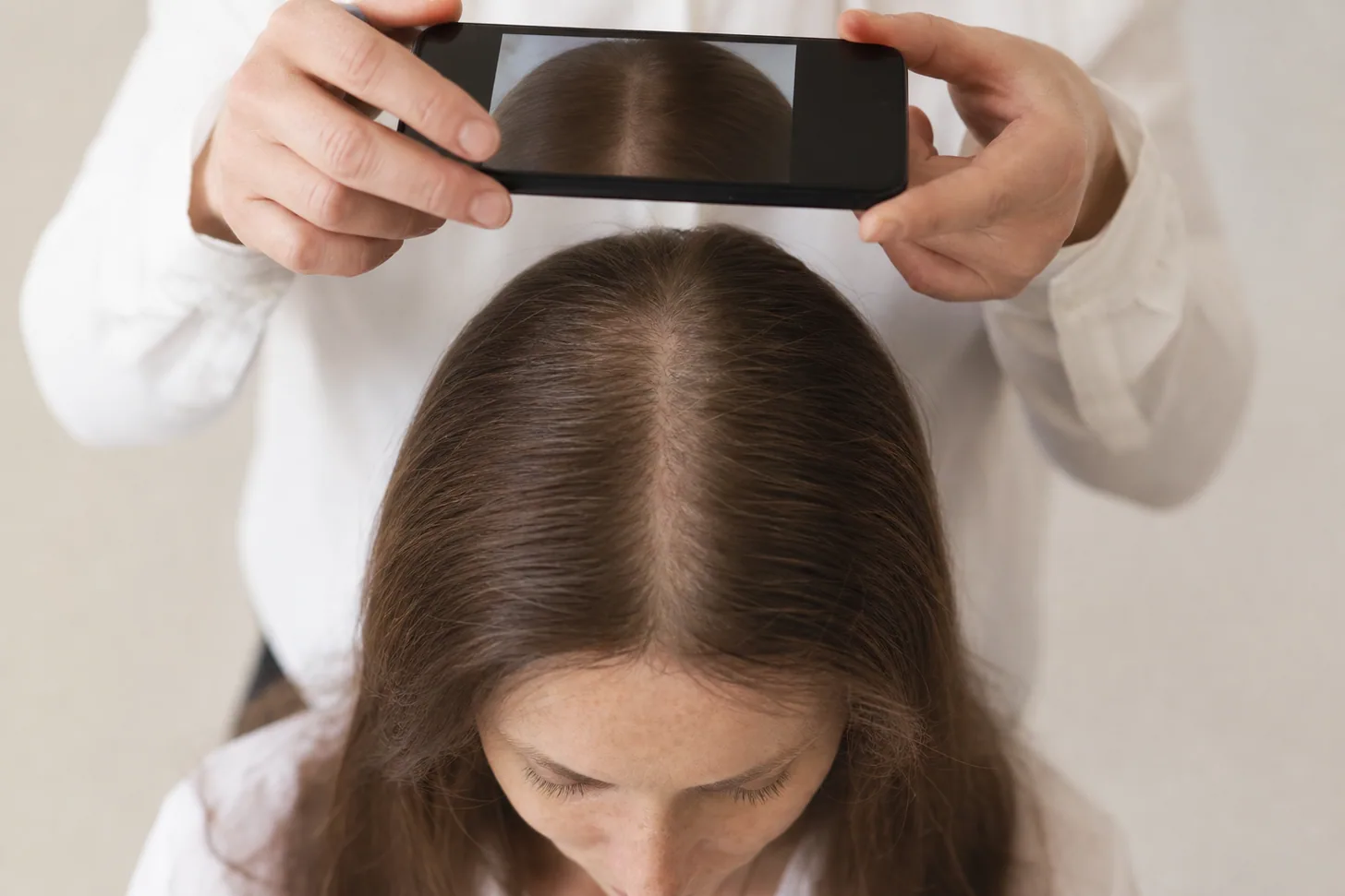 Phone photographing a center part line from above to track part width over time