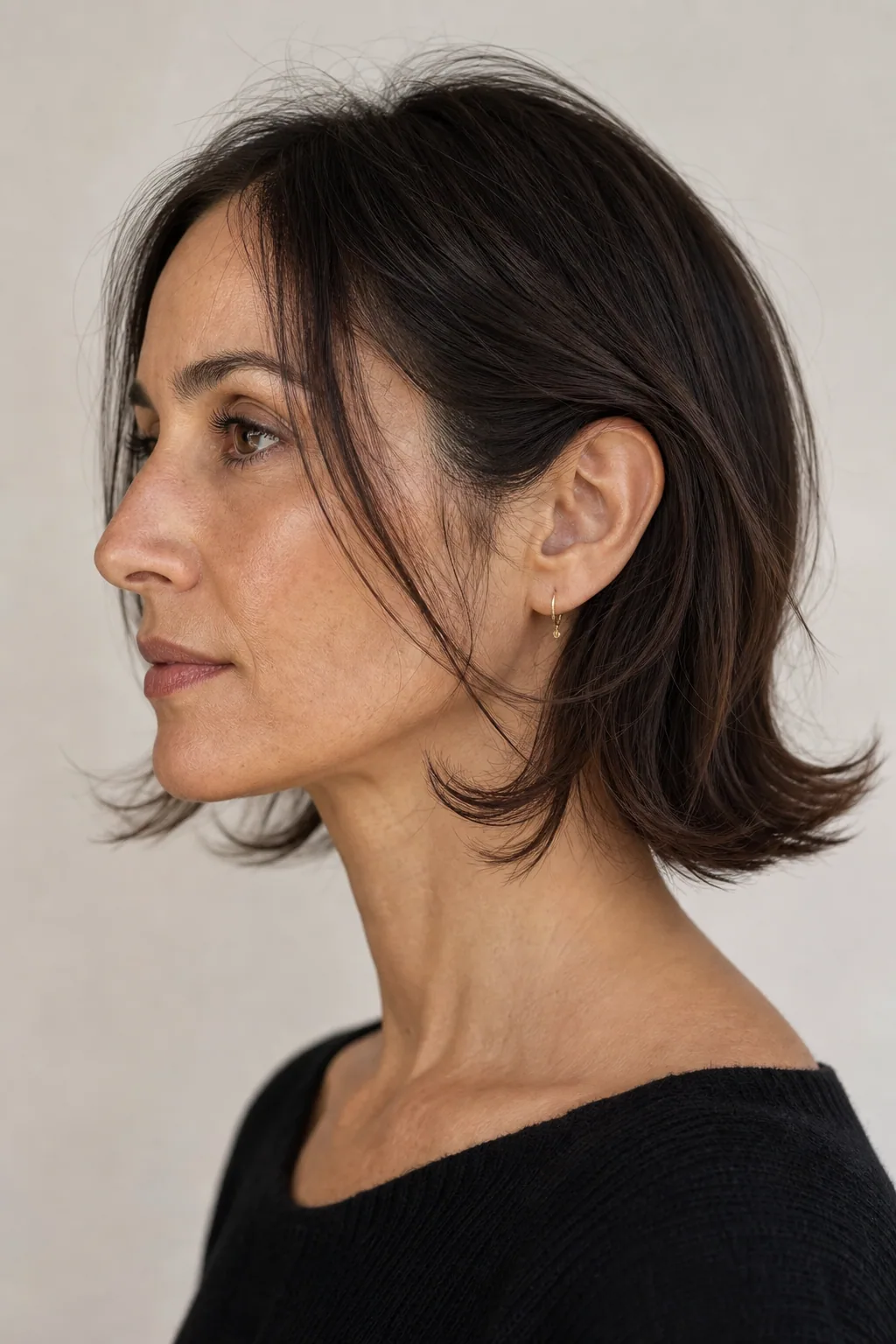 Fine hair in a shoulder-length cut with soft outward-flicking ends at jaw level, long face, side profile