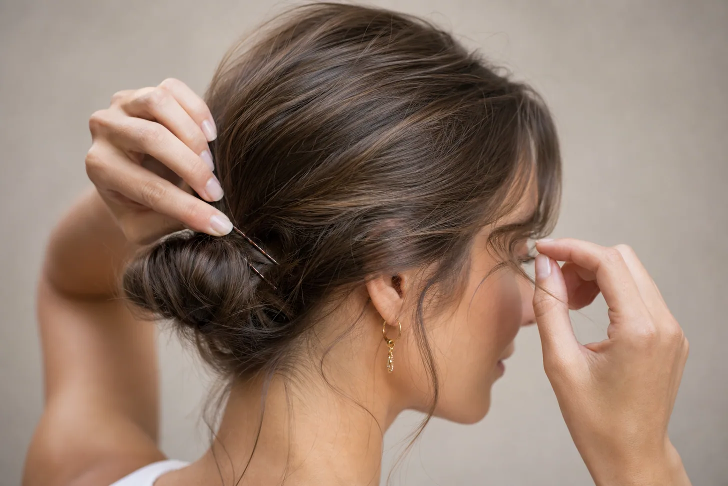 Bobby pins securing a twisted low bun on fine hair with pieces loosened for an undone look